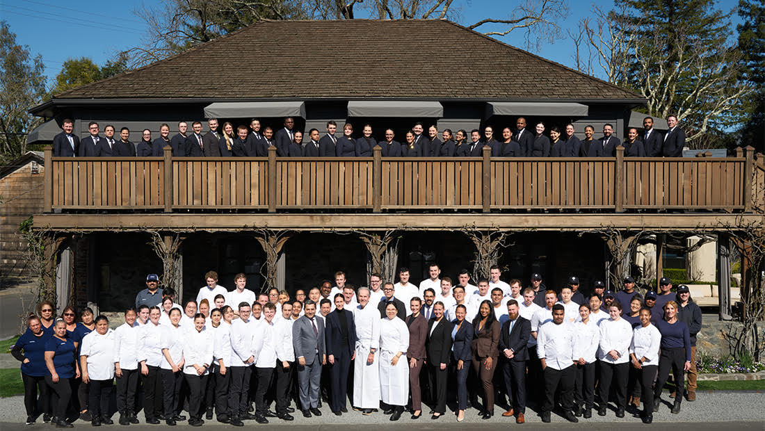 A large group of employees standing in front of an old building